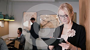 4k. young beautiful blonde businesswoman uses a touchscreen tablet in the modern startup office.