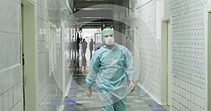 4K A young doctor in the medical form and a mask goes a long corridor in the old hospital.