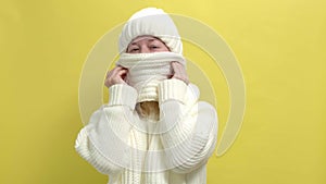 4k. Young smiling woman wearing white knitted sweater, scarf and hat