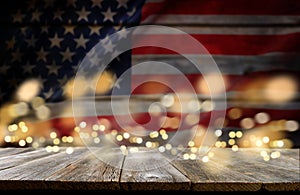 4th of July background. Empty wooden plank table with American USA flag and burning sparkler fireworks and golden lights bokeh