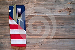 4th of July Rustic Picnic Table Place Setting with silverware and American Flag napkin with background of wood boards for copy spa