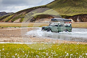 4WD car wades river in Landmannalaugar in Iceland