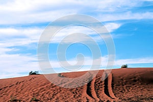4WD trail marks on a red Sand dune under blue sky