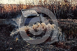 4x4 concept. SUV or offroader on mud road. Large rocks on the road extreme travel adventure in nature. Track on mud