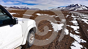 A 4x4 expedition vehicle passes through the surreal winter landscapes and snow capped mountain scenery in the SIloli Desert, Sud