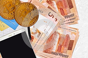 5 Belorussian rubles bills and golden bitcoins with smartphone and credit cards. Cryptocurrency investment concept. Crypto mining