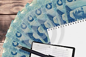 5 Canadian dollars bills fan and notepad with contact book and black pen. Concept of financial planning and business strategy