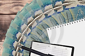 5 Canadian dollars bills fan and notepad with contact book and black pen. Concept of financial planning and business strategy