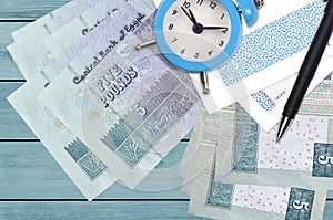 5 Egyptian pounds bills and alarm clock with pen and envelopes. Tax season concept, payment deadline for credit or loan. Financial