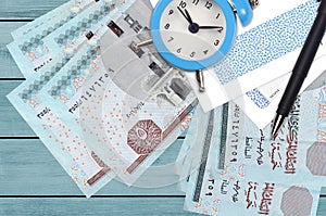 5 Egyptian pounds bills and alarm clock with pen and envelopes. Tax season concept, payment deadline for credit or loan. Financial