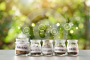 5 glass jars with coins arranged in a natural background, money saving concept and savings allocation for different purposes