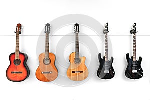 5 Guitars hanging in front of a white wall