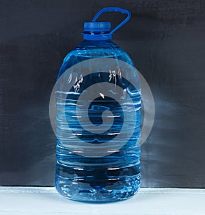 5 liters. Big plastic bottle of potable water on a dark background.