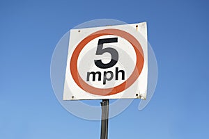 5 mph speed limit sign against blank empty blue sky