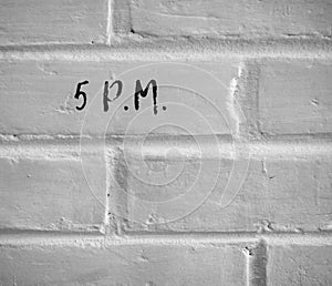 5 P.M. WRITTEN ON WHITE PLAIN BRICK WALL