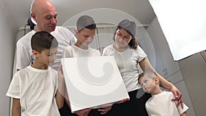 5 people three boys mom and dad Beautiful smiling family in white T-shirts hold in hands the big blank banner and Look