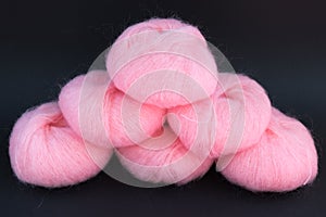 5 pink fluffy yarn balls on black background