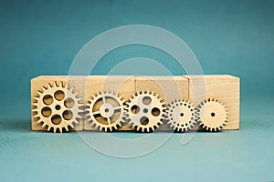 5 wooden gears standing leaning on wooden cubes