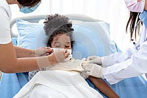5 year old African girl wearing a surgical mask Lying in a patient`s bed, being treatment by a team of doctor for flu virus infec