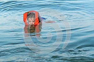 A 5 year old boy is kept on the water in the sea with the help of a life jacket.
