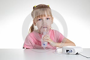 A 5-year-old caucasian girl is breathing into an inhaler at home. Treatment of cough and lung diseases in children, dilution of