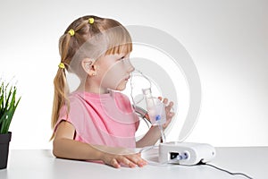 A 5-year-old caucasian girl is breathing into an inhaler at home. Treatment of cough and lung diseases in children, dilution of