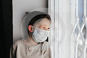5 years boy wearing surgical protection face mask sitting at home during corona virus,covid-19 outbreak. European child