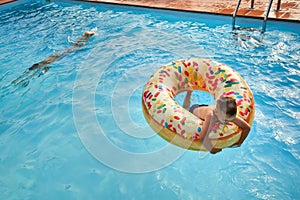 5 years old Boy in swimming pool on inflatable colorful ring