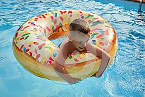 5 years old Boy in swimming pool on inflatable colorful ring