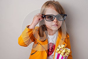 The 5 years old girl with sweet popcorn and cinema glasses