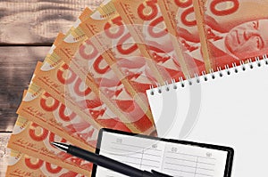 50 Canadian dollars bills fan and notepad with contact book and black pen. Concept of financial planning and business strategy