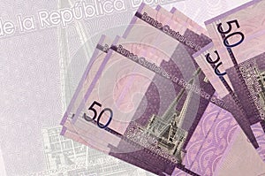 50 Dominican pesos bills lies in stack on background of big semi-transparent banknote. Abstract presentation of national currency
