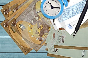 50 euro bills and alarm clock with pen and envelopes. Tax season concept, payment deadline for credit or loan. Financial