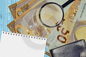 50 euro bills and magnifying glass with black purse and notepad. Concept of counterfeit money. Search for differences in details