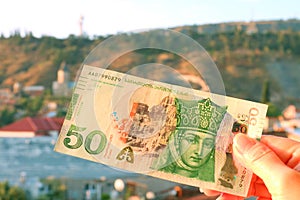 50 Georgian Lari Banknotes in Obverse Side in Hand with Tbilisi City View in Backdrop