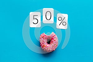 50% off discount - sale concept with bitten donut - on blue background top-down copy space