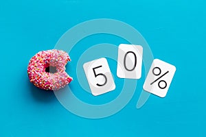 50% off discount - sale concept with bitten donut - on blue background top-down copy space