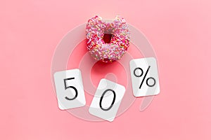 50% off discount - sale concept with bitten donut - on pink background top-down