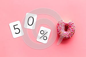 50% off discount - sale concept with bitten donut - on pink background top-down