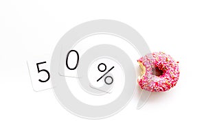 50% off discount - sale concept with bitten donut - on white background top-down copy space