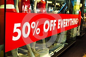 50% off everything sale red sign on shop front glass window.