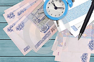 50 russian rubles bills and alarm clock with pen and envelopes. Tax season concept, payment deadline for credit or loan. Financial