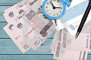50 russian rubles bills and alarm clock with pen and envelopes. Tax season concept, payment deadline for credit or loan. Financial