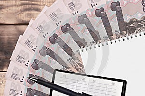 50 russian rubles bills fan and notepad with contact book and black pen. Concept of financial planning and business strategy