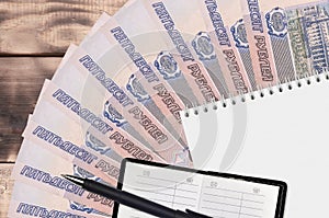 50 russian rubles bills fan and notepad with contact book and black pen. Concept of financial planning and business strategy