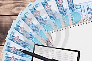 50 Sri Lankan rupees bills fan and notepad with contact book and black pen. Concept of financial planning and business strategy