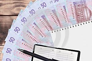 50 Ukrainian hryvnias bills fan and notepad with contact book and black pen. Concept of financial planning and business strategy