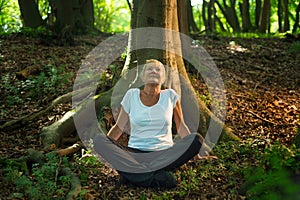 50 years old woman enjoys forest bathing with all her senses. Shinrin Yoku