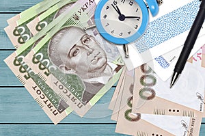 500 Ukrainian hryvnias bills and alarm clock with pen and envelopes. Tax season concept, payment deadline for credit or loan.