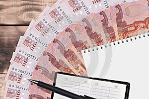 5000 russian rubles bills fan and notepad with contact book and black pen. Concept of financial planning and business strategy